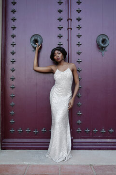 Vertical image of beautiful Black woman in a gold dress posing outdoor.