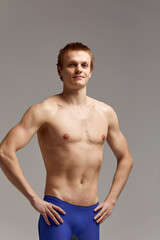 Fototapeta premium Young swimmer in excellent physical shape, on a gray background with copy space, call for sports, advertising banner