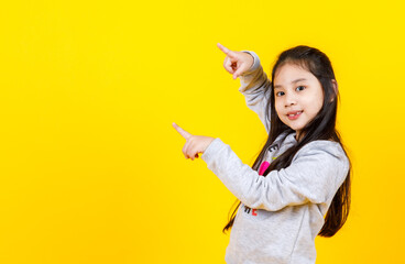 Lovely Asian girl wearing sweater smiling and enjoy gesturing hand sign to point fingers up to desired message at copy space to recommend winter benefit offer from isolated portrait of happy kid - Powered by Adobe