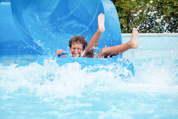 happy an 8 year old boy is riding in the water Park on inflatable circles on water slides with...