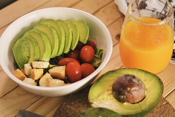 Fresh salad with avocado tomato and crouton on wooden table.