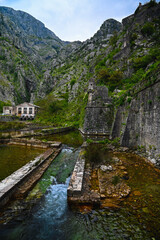 Fototapeta na wymiar River flowing along the walls of Old Kotor, using an ancient aqua duct still in use today.