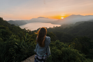 The girl meets the dawn in the mountains with a gorgeous view of the mountains and lakes