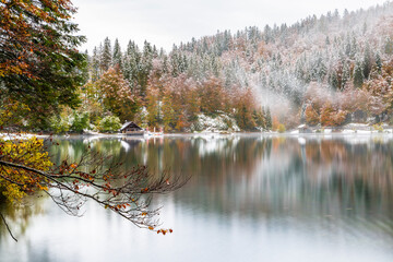 Between autumn and winter. Warm and cold reflections of snow on Lake Fusine.