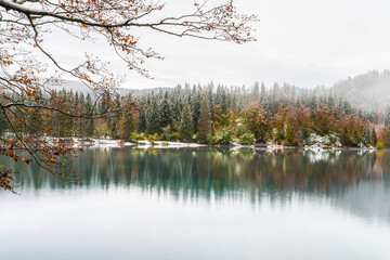 Between autumn and winter. Warm and cold reflections of snow on Lake Fusine.