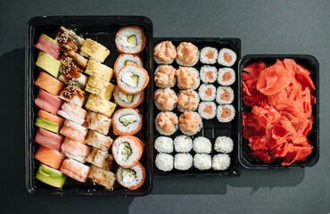 Japanese food concept. Catering, various kinds of sushi on plate. Placed on stone black background in plastic delivery box. Sushi roll (Philadelphia) with salmon, smoked eel, avocado, cream cheese.