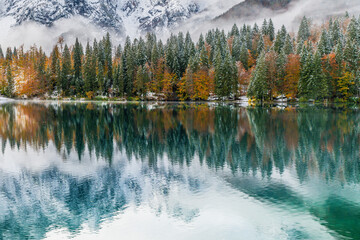 Between autumn and winter. Warm and cold reflections of snow on Lake Fusine.