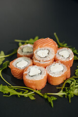 Sushi roll (Philadelphia) with salmon, smoked eel, avocado, cream cheese on black background. Sushi menu. Japanese food.