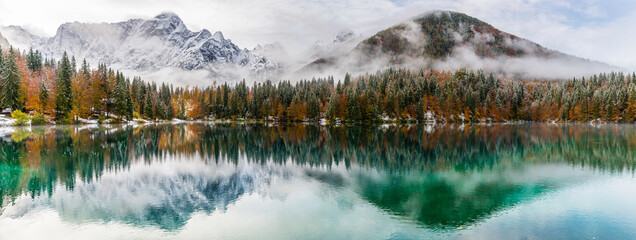 Between autumn and winter. Warm and cold reflections of snow on Lake Fusine.