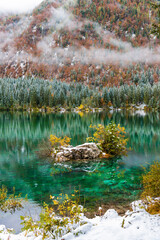 Between autumn and winter. Warm and cold reflections of snow on Lake Fusine.