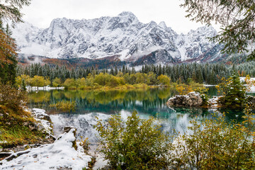 Fototapeta na wymiar Between autumn and winter. Warm and cold reflections of snow on Lake Fusine.
