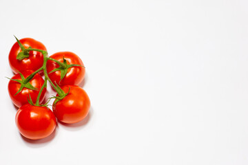 red organic tomatoes on a green branch on a white background