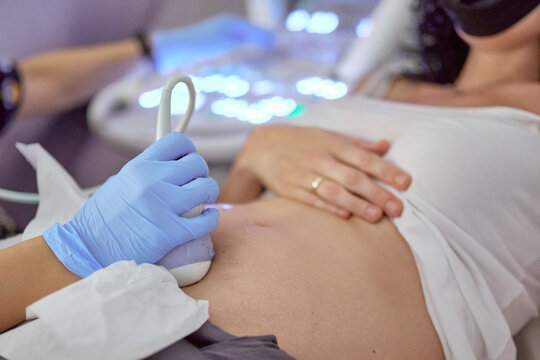 hands of a female doctor performing an ultrasound on a pregnant woman in a hospital. concept gestation and health care in pregnancy