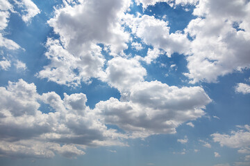 Naklejka na ściany i meble Fluffy cumulus clouds on blue sky background. Cloudscape white and grey color