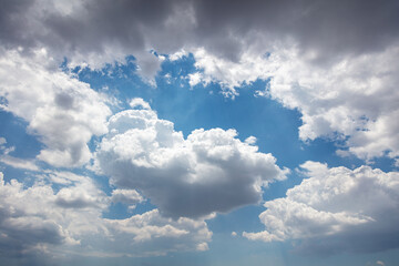 Fluffy cumulus clouds on blue sky background. Cloudscape white and grey color