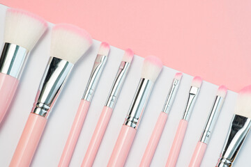 Set of professional, natural makeup brushes. Luxury pink make up brushes in silver and pink colours on a white and pink background