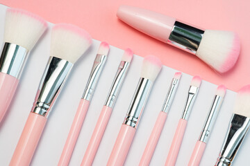 Set of professional, natural makeup brushes. Luxury pink make up brushes in silver and pink colours on a white and pink background