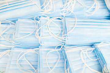Fototapeta na wymiar Pile of medical masks stacked and ready for shipping. Close up of blue respiratory face masks.