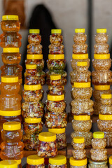 There are many jars of organic, natural honey on the counter for sale. Different honey, different colors in plastic cans are ready for sale at the honey fair. Nuts filled with honey. 