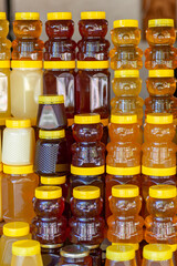 There are many jars of organic, natural honey on the counter for sale. Different honey, different colors in plastic cans are ready for sale at the honey fair. Nuts filled with honey. 