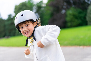 Fototapeta na wymiar Happy little boy wearing safety helmet. Close up portrait of a smiling child walking in a park.