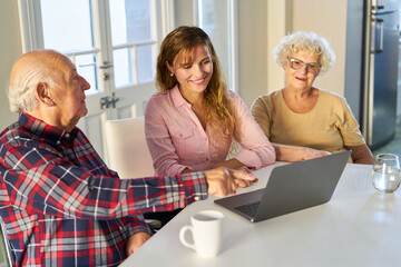 Curious senior couple with daughter on laptop computer