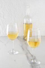 Vertical image of two wine glasses and bottle of white wine on the marble table.Testing sweet wine