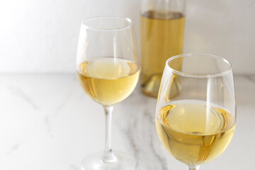 Closeup of two wine glasses and white whine,bottle on the white table.Empty space