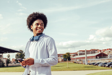 Portrait of afro guy using smartphone outdoors