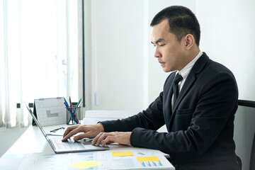 Fototapeta premium Businessman boss in suit to analysis of investments in new business from chart and document during to typing new idea