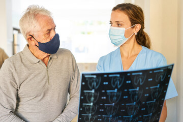 Doctor and a senior with face mask discuss MRI