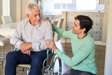 Smiling man taking care of senior man in wheelchair