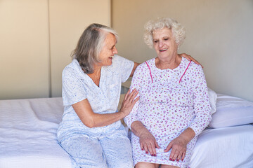 Laughing elderly woman comforts sick friend in hospital