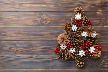 Christmas tree made from natural cones on colored background, view from above. New Year minimal concept with copy space