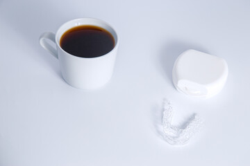 Isolated invisalign braces concept with cup of a coffee over white.