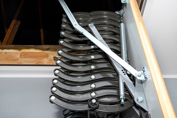 Folding metal stairs to the attic in the ceiling, open hatch and complex stairs, modern look.