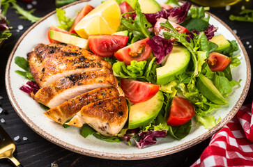 Healthy food concept. Grilled chicken with fresh salad at dark wooden table.