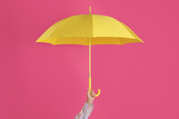 Woman with open yellow umbrella on pink background, closeup
