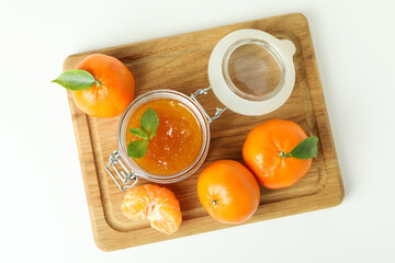 Board with mandarin jam and ingredients on white background
