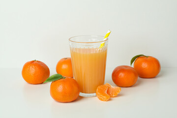 Glass of mandarin juice and ingredients on white background
