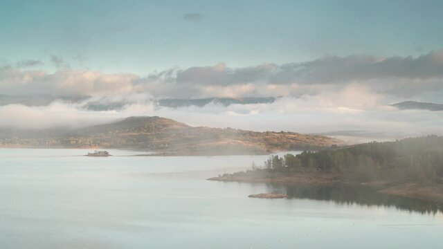 Morning landscape. Time lapse of fog and clouds moving over lake Embalse de Aguilar de Campoo in province of Palencia, Castile and Leon community, northern Spain.