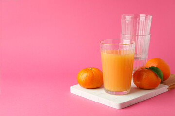 Board with mandarin juice and ingredients on pink background