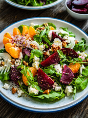  Beetroots salad with feta cheese, walnuts and tangerines on wooden background
