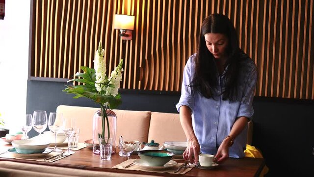a woman reading to date setting a table in her house