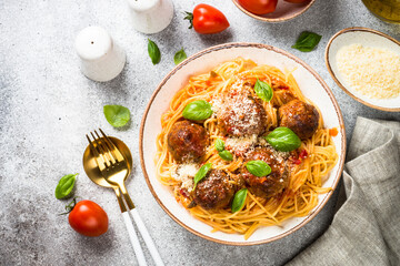 Pasta with Meatballs in tomato sauce, basil and parmesan on stone table.