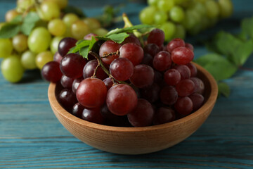 Bowl with red grape and green grape on wooden background