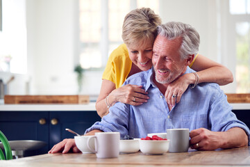 Loving Retired Couple Sitting Around Table At Home Having Healthy Breakfast Together