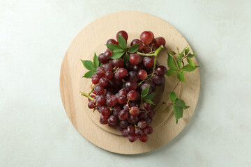 Wooden tray with grape on white textured background