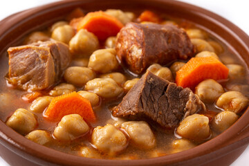 Traditional Spanish cocido madrileño in bowl isolated on white background. Close up