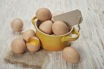 Bowl of raw chicken eggs on the wooden background